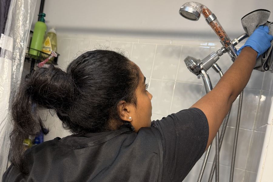 Integrante del equipo de Smith Fresh & Clean limpiando una regadera